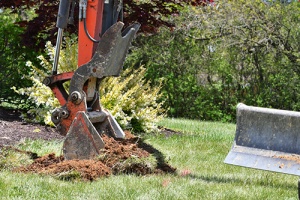 Backhoe beginning to dig up lawn for a pool after area was cleared by tree companies in Freehold expert