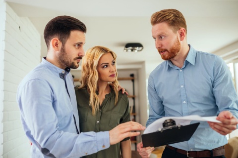 Real estate agent reviewing property documents on a clipboard with a couple buying Seaside Park real estate